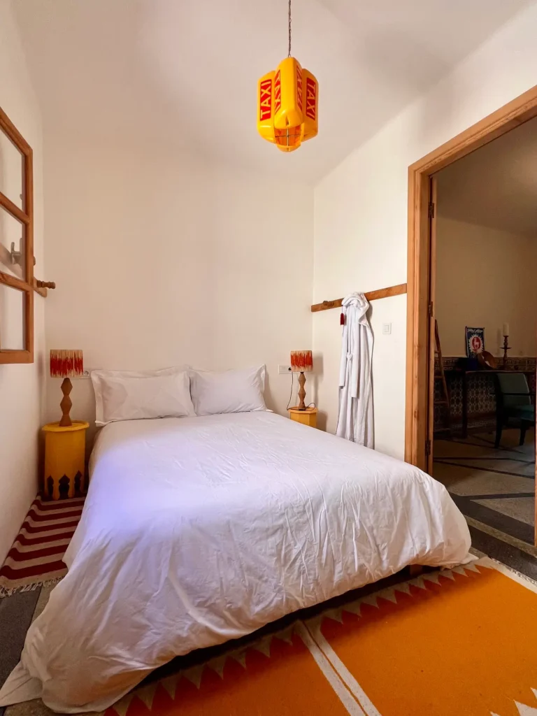 Traditional blue shutters and wooden windows filling the bedroom with natural light at Tizwa Beach Apartment, Essaouira.