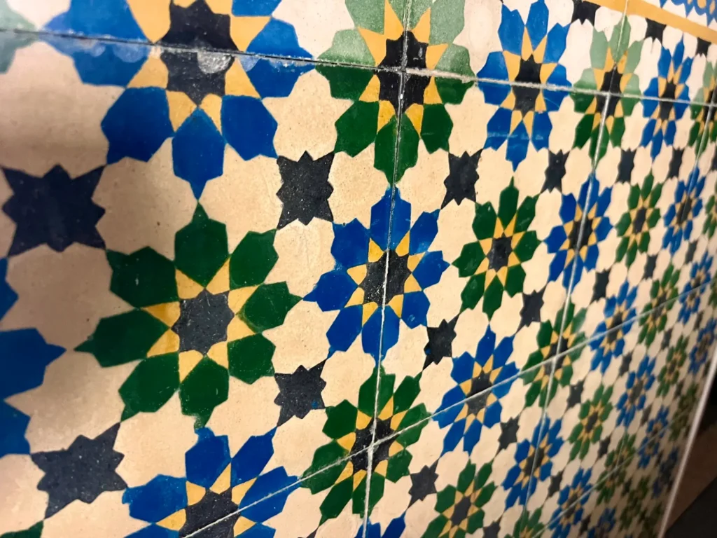 Close-up of handmade Moroccan geometric tilework inside Tizwa Beach Apartment.