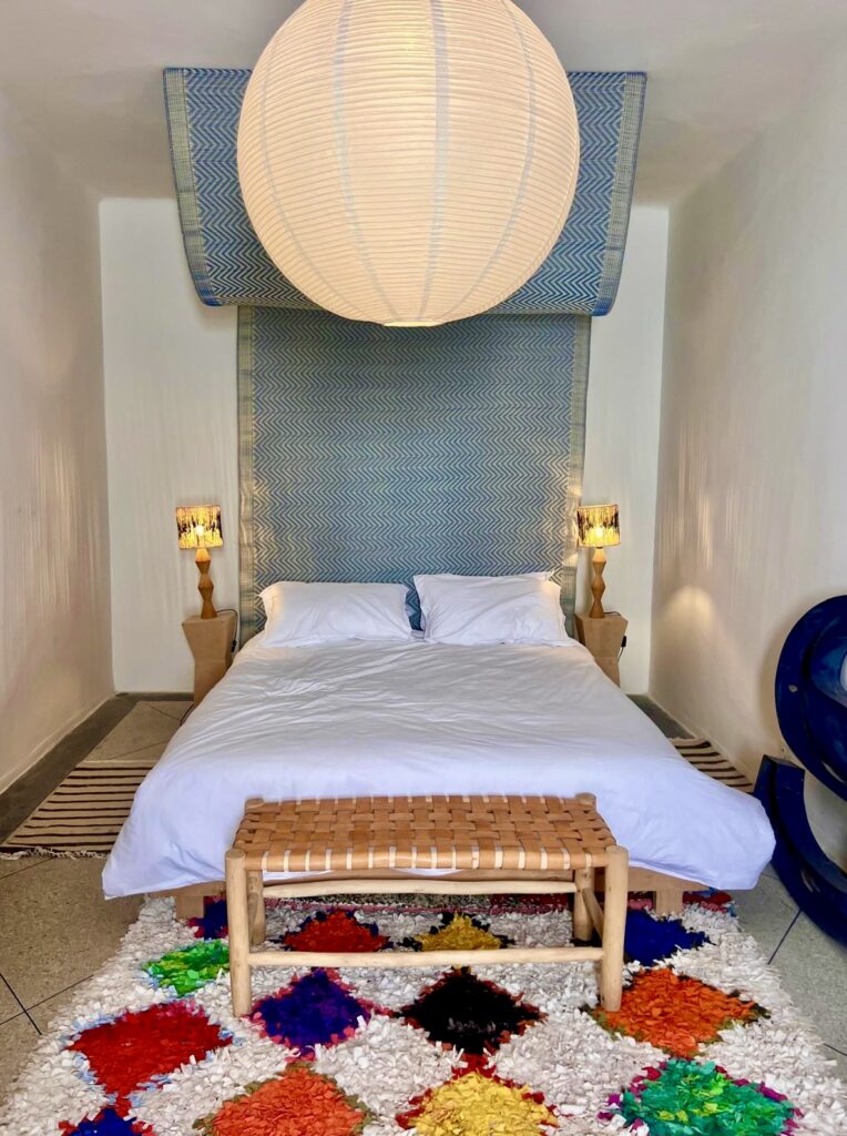 Spacious contemporary bedroom at Tizwa Beach Apartment with designer lighting and handcrafted Moroccan rug.